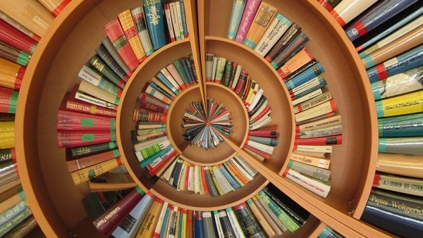 Aerial view of a spiral bookshelf with colorful volumes lining the steps. 